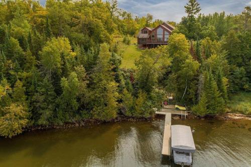 a house sitting on top of a river with a bridge at Spacious Leech Lake Home on 2 Private Acres, 200' of lake shore 15 Minutes to Walker with boat lift, dock, swimming, fire pit in Walker