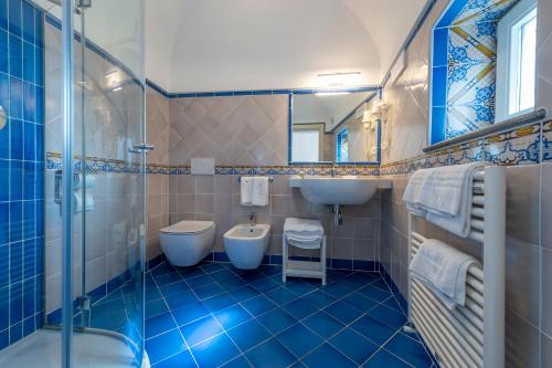 a blue tiled bathroom with two toilets and a sink at Albadamare Boutique Hotel in Praiano