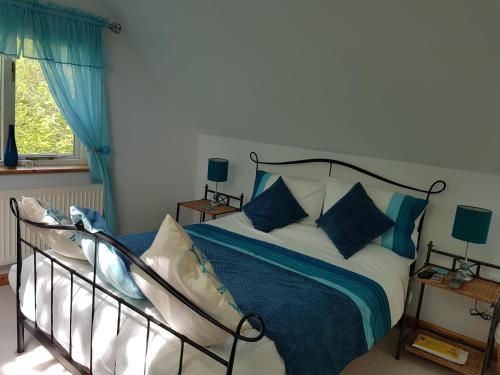 a bedroom with a bed with blue and white pillows at Meadow Oak Accommodation in Bodmin