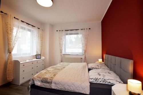 a bedroom with a bed and a dresser and two windows at Ferienwohnung Schmalkalden am Radwanderweg in Schmalkalden