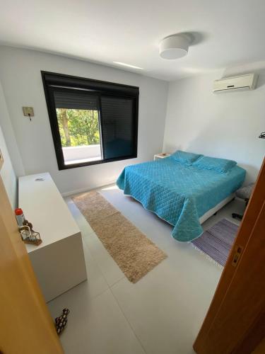 um quarto com uma cama azul e uma janela em Casa de hóspede Dunas do Siriú em Garopaba