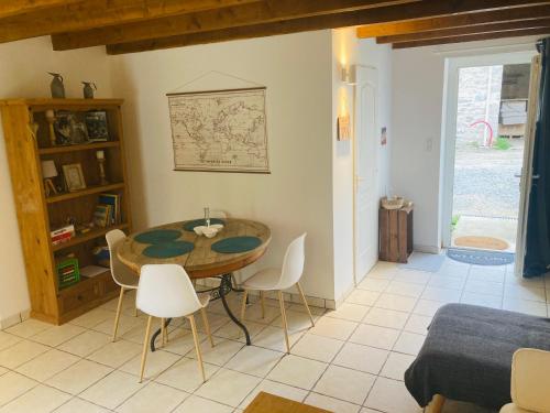 un salon avec une table en bois et des chaises blanches dans l'établissement Petite maison à la campagne, à Saint-Germain