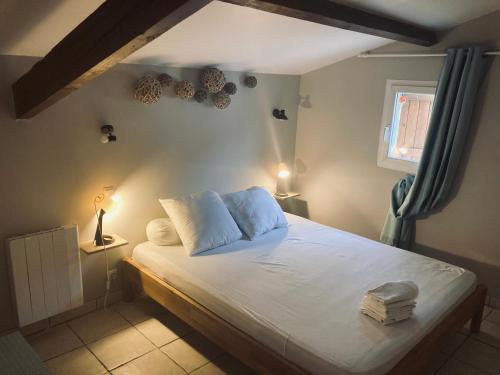um quarto com uma cama com lençóis brancos e uma janela em Petite maison à la campagne em Saint-Germain