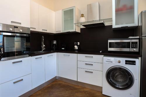 une cuisine avec des armoires blanches et une laveuse et une sécheuse dans l'établissement IMMOGROOM - Terrace with sea view - AC - Suquet - 5 min from the beach, à Cannes