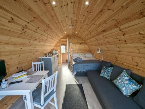 Habitación con sofá y cama en una cabaña de madera. en Orchard Luxe Glamping Pod en Dungannon