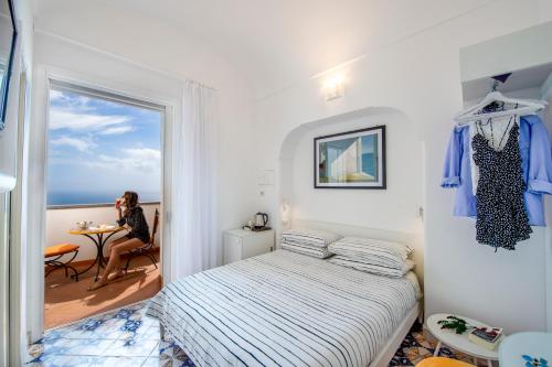 a bedroom with a bed and a woman sitting at a table at Albadamare Boutique Hotel in Praiano
