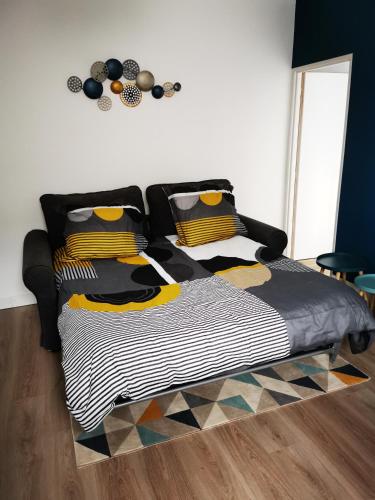 a bed with a black and yellow comforter in a room at Le Puzzle in Trélazé