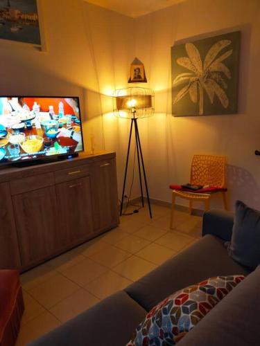 un salon avec un canapé et une télévision à écran plat dans l'établissement Maison au coeur de Saint-Gilles L'Inattendue, à Saint-Gilles-Croix-de-Vie