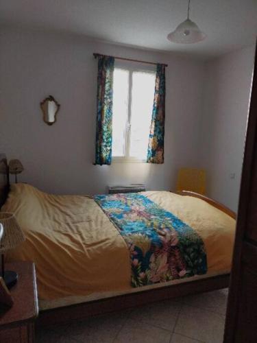 Ce lit se trouve dans une chambre dotée d'une fenêtre et d'un couvre-lit. dans l'établissement Maison au coeur de Saint-Gilles L'Inattendue, à Saint-Gilles-Croix-de-Vie
