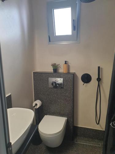 a bathroom with a toilet and a sink and a window at Tiny studio 2 min walking distance from the port in Volos