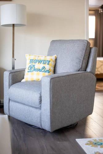 a gray chair with a yellow pillow on it in a living room at King & Queen Memory Foam Beds 2-2b Georgetown Villas in Fairview Park