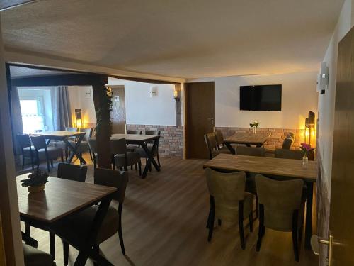 Hotel Unter den Linden في Kierspe: مطعم بطاولات وكراسي خشبية وتلفزيون