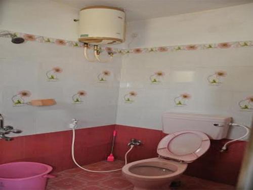 a bathroom with a pink toilet and a pink bucket at Hill Heaven Home Stay in Kodaikānāl