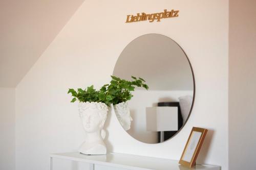 a mirror on a shelf with a vase with a plant at Lichtdurchflutende Wohnoase-Stilvoll-ruhig-Parkplatz-Self Check-Langzeit-5 Personen in Paderborn