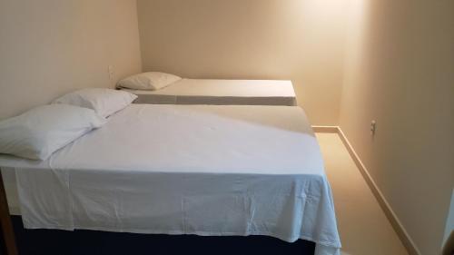 two beds in a room with white sheets and pillows at Pousada Vibe Guajiru in Trairi