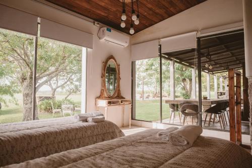 two beds in a room with large windows and a table at El Rincón. Farm and Lodge in Carmelo