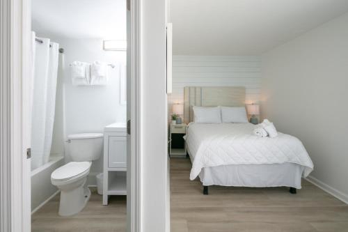 a white bedroom with a bed and a toilet at Lily & Bloom in Myrtle Beach