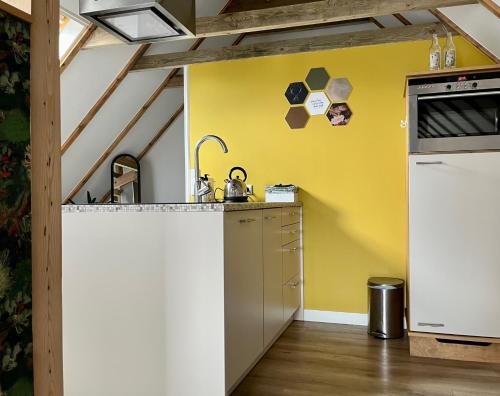 uma cozinha com um balcão e uma parede amarela em Hústerheide em Noordbergum