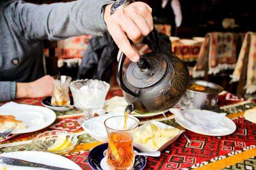 een persoon die thee in een theepot giet op een tafel bij Qiz Galasi Hotel Baku in Baku