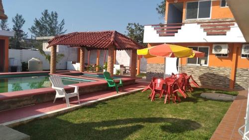 a yard with chairs and umbrellas next to a house at Hotel Valeria in Tecolutla