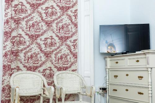 a room with two chairs and a tv and a dresser at Alojamiento Turístico "La Condesa Carmen" in Manzanares