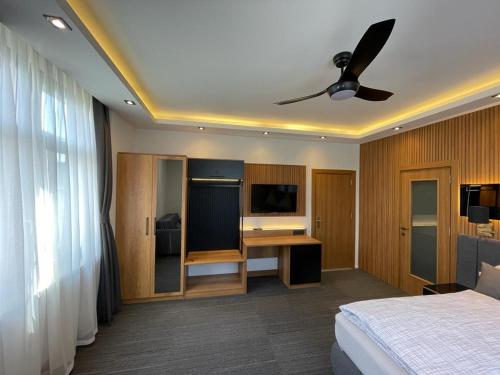Schlafzimmer mit einem Bett und einem Schreibtisch mit einem Deckenventilator in der Unterkunft Uhldinger-Hof in Uhldingen-Mühlhofen