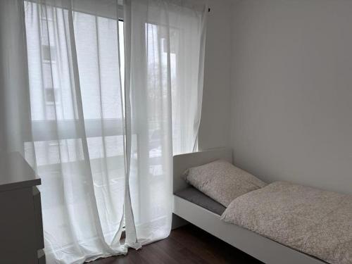 美茵河畔哈瑙的住宿－Exklusives Apartment für 5 Personen in der Nähe von Frankfurt，一间卧室配有床和白色窗帘的窗户