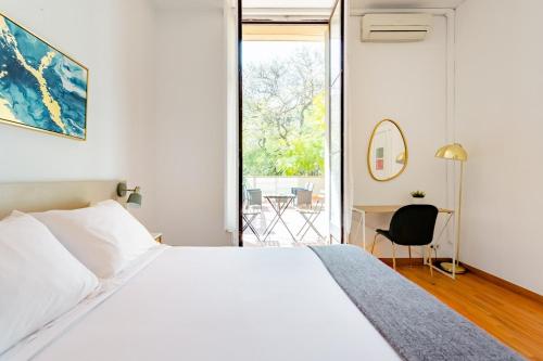 1 dormitorio con 1 cama blanca grande y escritorio en Casa Lolita, en Barcelona