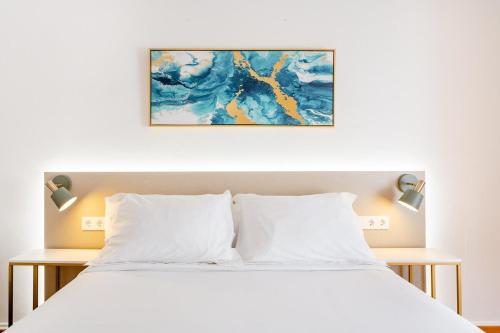 Un dormitorio con una cama blanca y una pintura en la pared en Casa Lolita, en Barcelona