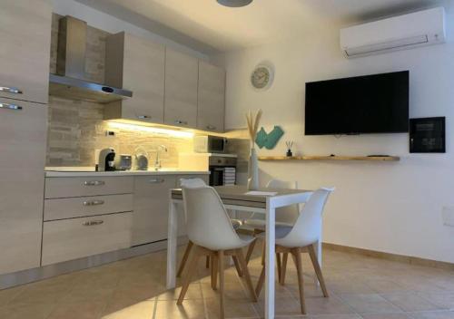 a kitchen with a table and chairs and a tv at [Loft Comodo ed Elegante] • Wi-Fi e Colazione in Sanluri
