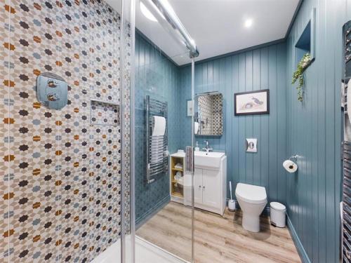 a bathroom with a toilet and a glass shower at Blacksmiths Cottages in Filey