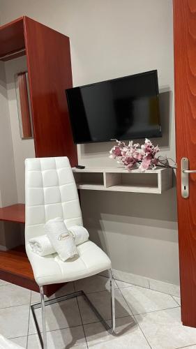 a living room with a white chair and a flat screen tv at PREMIUM SUITES in Ofrínion