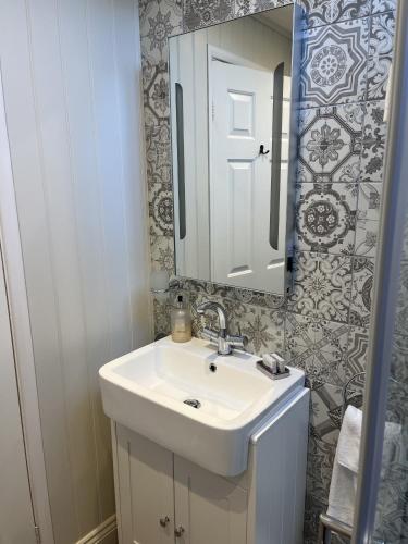 a bathroom with a white sink and a mirror at Blacksmiths Cottages in Filey