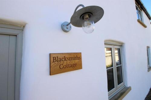 una luz en una pared blanca con un cartel en ella en Blacksmiths Cottages en Filey