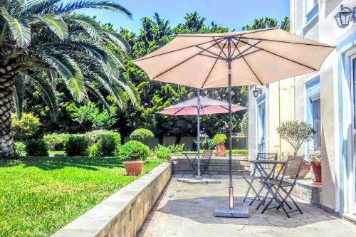 un patio con 2 sillas y una sombrilla en Anastasia's Garden - Yellow Apartment, en Moúdhros