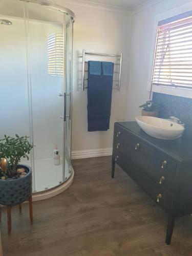 a bathroom with a sink and a glass shower at Blue Bell Cottage. Serene luxury farmstead in Lower Moutere