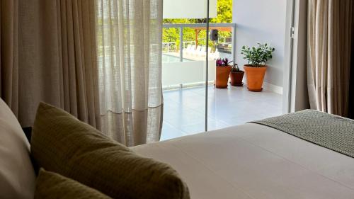 a bedroom with a bed and a balcony with plants at Resort Ecoar in Gaspar