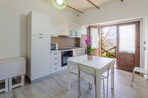 Una cocina con gabinetes blancos y una mesa con sillas. en Il Tramonto Holidays, en Trevi