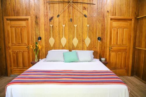 POUSADA BAWARY في سائو غابريل دا كاشويرا: غرفة نوم بسرير وجدران خشبية ودوائن خشبية