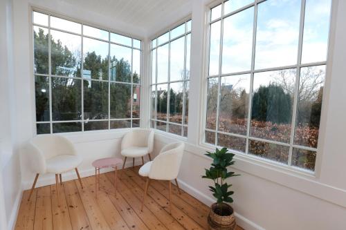 Habitación con sillas blancas y ventanas grandes. en Scandi-Hygge Seaside House - only 10mins to Copenhagen, en Charlottenlund