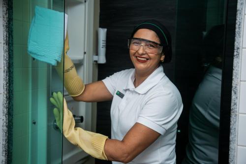 a woman is smiling as she is cleaning a glass door at ibis Styles Belem Batista Campos in Belém