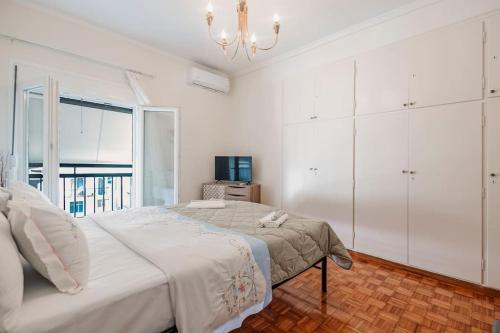 a white bedroom with a bed and a chandelier at M&R HOME in Mantoúkion