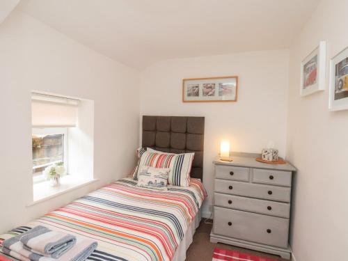 a small bedroom with a bed and a dresser at Mill Cottage in Saltburn-by-the-Sea