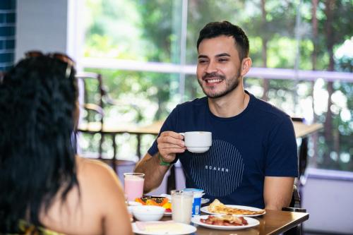 a man sitting at a table with a cup of coffee at ibis Styles Belem Batista Campos in Belém