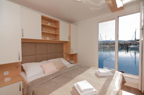 a bedroom with a large bed with a large window at Eldamar Floating House Portorož in Portorož