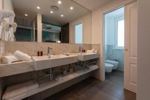 a bathroom with two sinks and a large mirror at Loriana Park Hotel Sul Lago in Bolsena