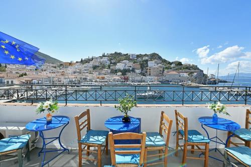 un gruppo di tavoli e sedie su un balcone di Delfini Hotel a Hydra