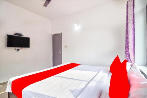 Calangute Ocean Wave في باغا: سرير احمر وبيض في غرفة بها تلفزيون