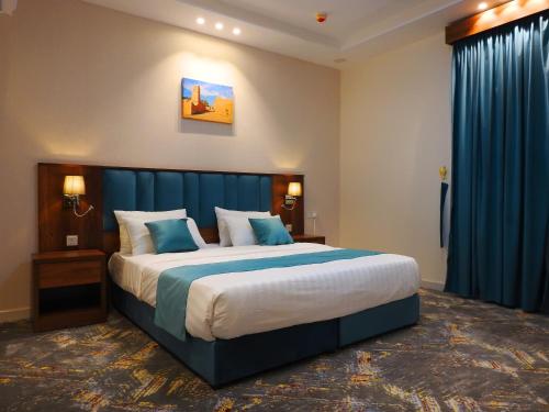 a bedroom with a large bed with blue curtains at انباك للشقق المخدومه in Abha