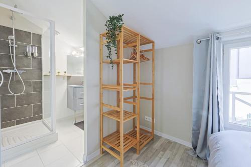 - une salle de bains avec une étagère en bois à côté d'une douche dans l'établissement La Maisonnette 20 minutes de Disney, à Villenoy